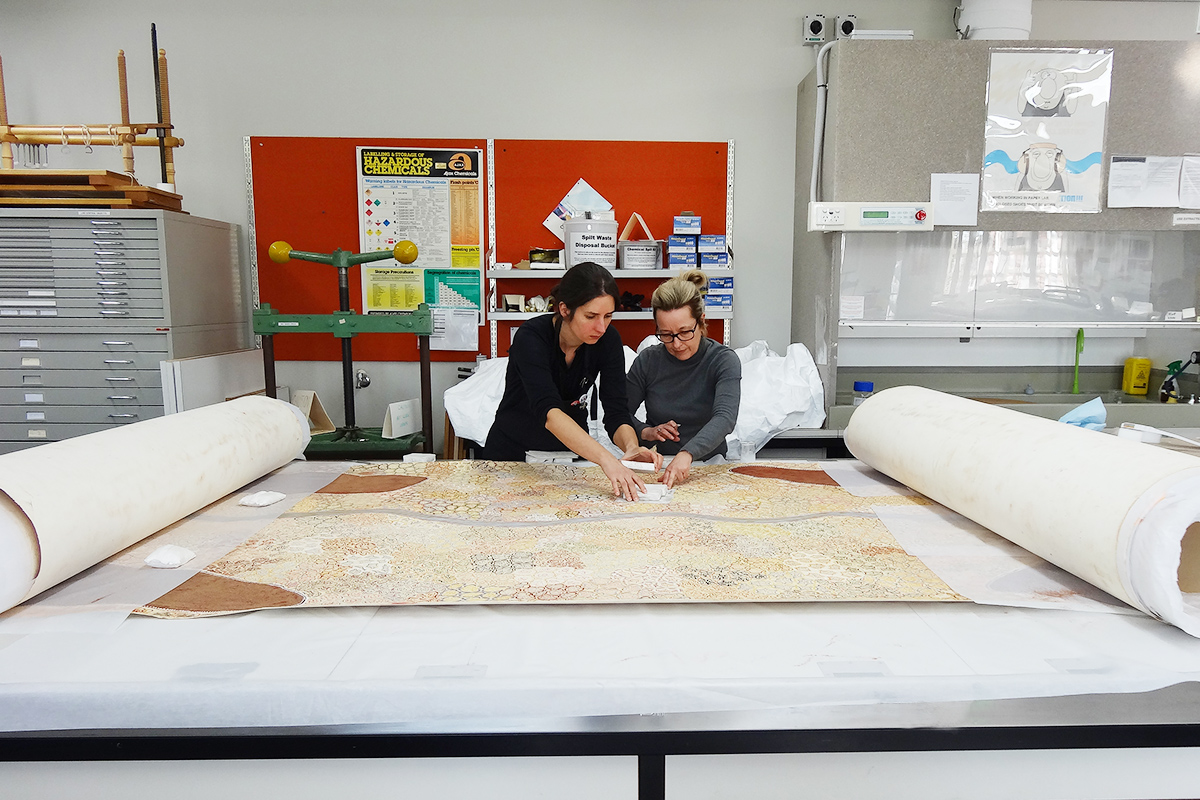 Senior Paper Conservator Aquila Evill and Conservation Technician Anna Austin, working on Being in Country – Woorrilbem to Thamberalm, Peggy Griffiths-Madij, Tarnanthi 2019 Artlab Australia. Image: Artlab Australia.