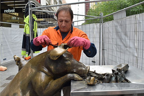 Conservator cleaning a sculpture after it has been vandalised