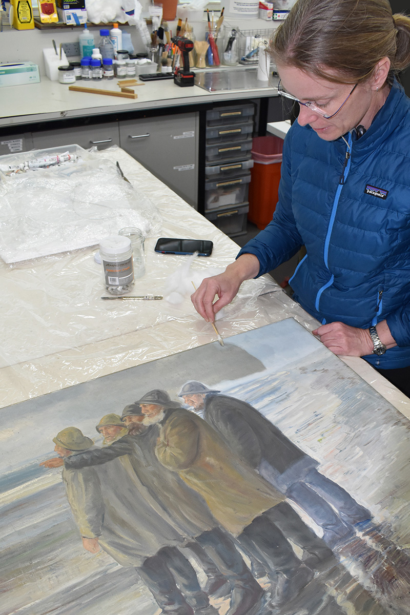 Conservator cleaning a painting